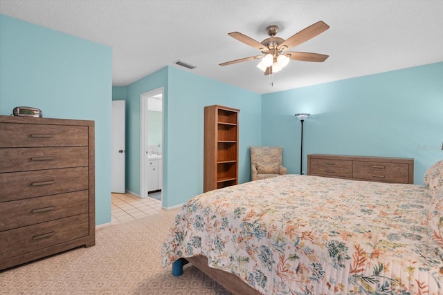 bedroom with ensuite bathroom, a textured ceiling, light carpet, and ceiling fan