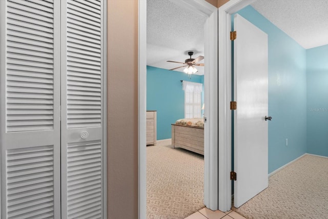 hall with light colored carpet and a textured ceiling