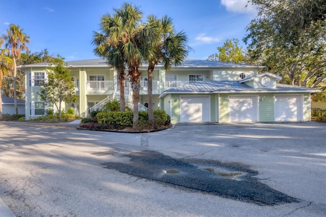 294 Hidden Bay Dr Unit 203, Osprey, FL 34229 - view of front of house with asphalt driveway, stairway, an attached garage, a metal roof, and a porch