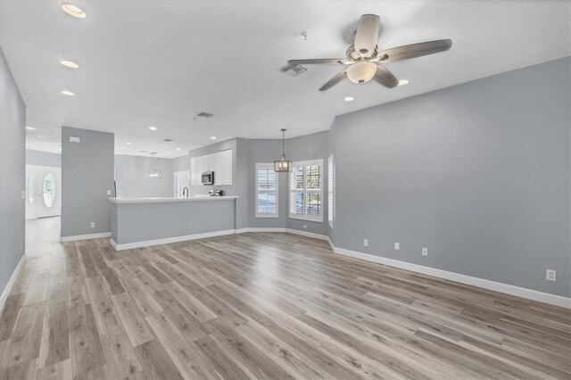 unfurnished living room featuring ceiling fan, light wood-type flooring, and sink