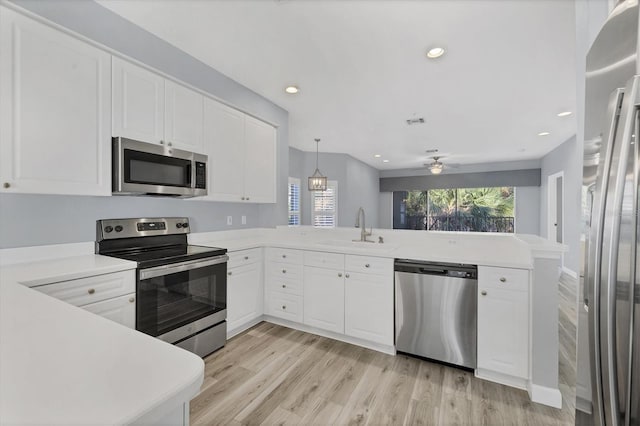 kitchen featuring ceiling fan, sink, kitchen peninsula, decorative light fixtures, and appliances with stainless steel finishes