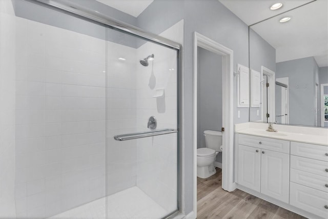 bathroom with wood-type flooring, vanity, toilet, and walk in shower