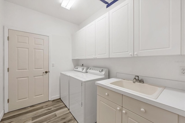 washroom with cabinets, separate washer and dryer, light hardwood / wood-style floors, and sink