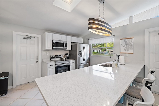 kitchen featuring pendant lighting, a kitchen breakfast bar, appliances with stainless steel finishes, and white cabinetry