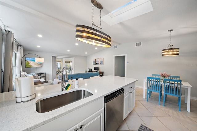 kitchen with light stone counters, sink, light tile patterned floors, stainless steel dishwasher, and white cabinetry