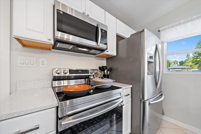 kitchen with white cabinetry, appliances with stainless steel finishes, light tile patterned floors, and light stone countertops