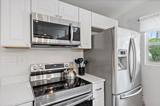 kitchen with white cabinetry, appliances with stainless steel finishes, and light stone counters