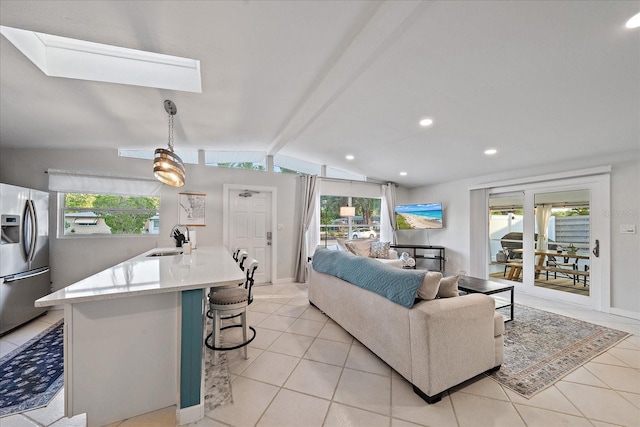 tiled living room featuring lofted ceiling with beams, sink, and plenty of natural light