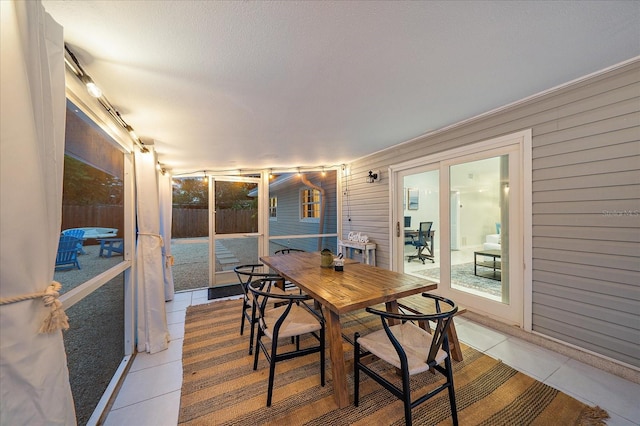 dining space with a textured ceiling, wood walls, and light tile patterned floors