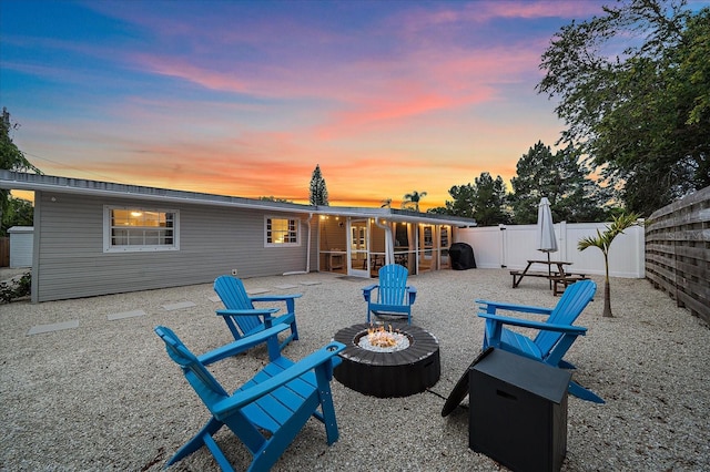 back house at dusk with an outdoor fire pit and a patio