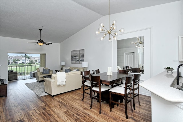 dining area featuring vaulted ceiling, dark hardwood / wood-style floors, and ceiling fan with notable chandelier