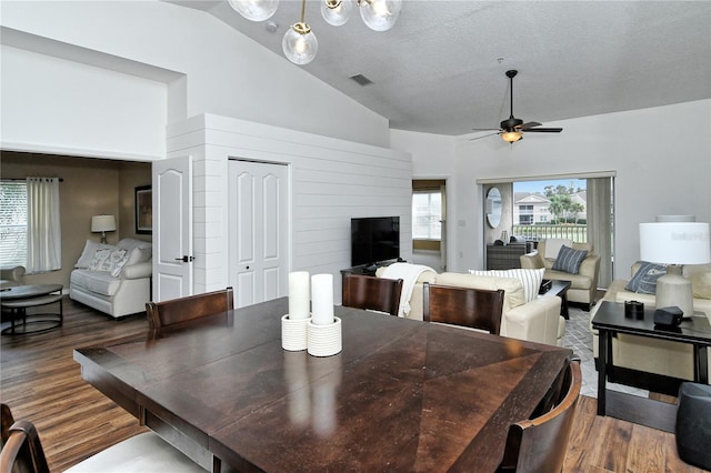 dining area with dark wood-type flooring, lofted ceiling, a textured ceiling, and ceiling fan