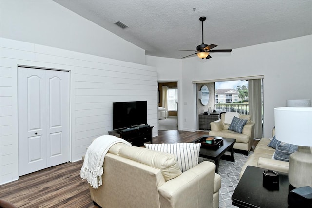 living room featuring dark wood-type flooring, vaulted ceiling, ceiling fan, and a textured ceiling