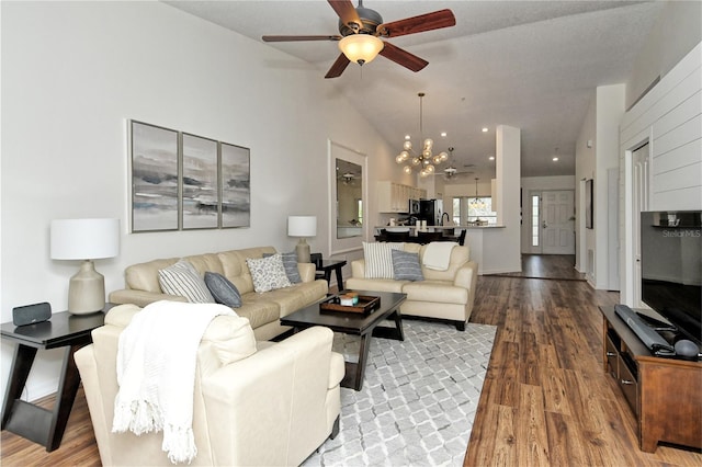 living room featuring hardwood / wood-style floors, ceiling fan with notable chandelier, and lofted ceiling