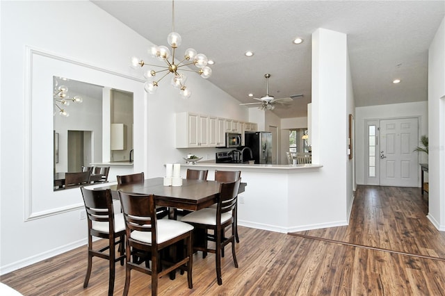 dining area featuring dark hardwood / wood-style floors, a textured ceiling, ceiling fan with notable chandelier, and high vaulted ceiling