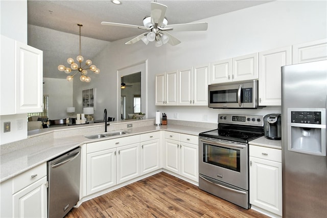 kitchen with sink, white cabinets, vaulted ceiling, and stainless steel appliances