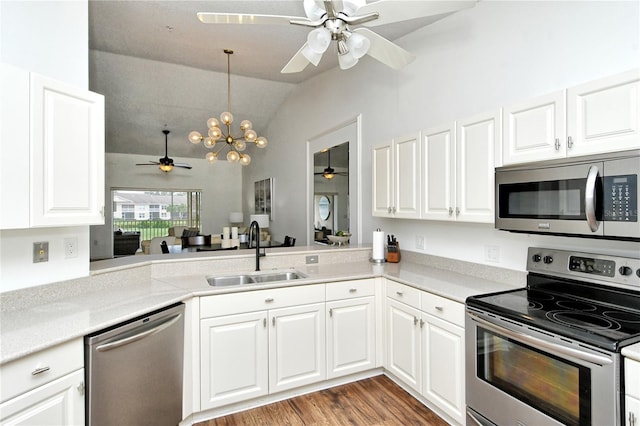 kitchen with appliances with stainless steel finishes, sink, white cabinets, kitchen peninsula, and lofted ceiling