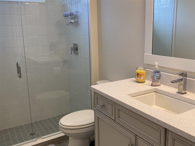 bathroom featuring a shower with door, vanity, and toilet