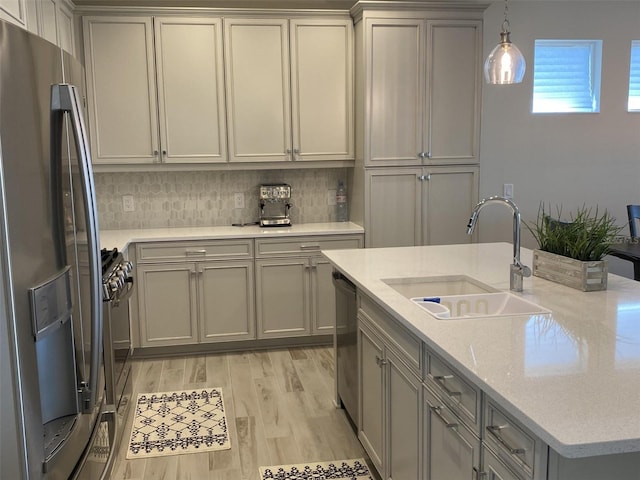 kitchen featuring decorative light fixtures, stainless steel appliances, gray cabinets, and sink