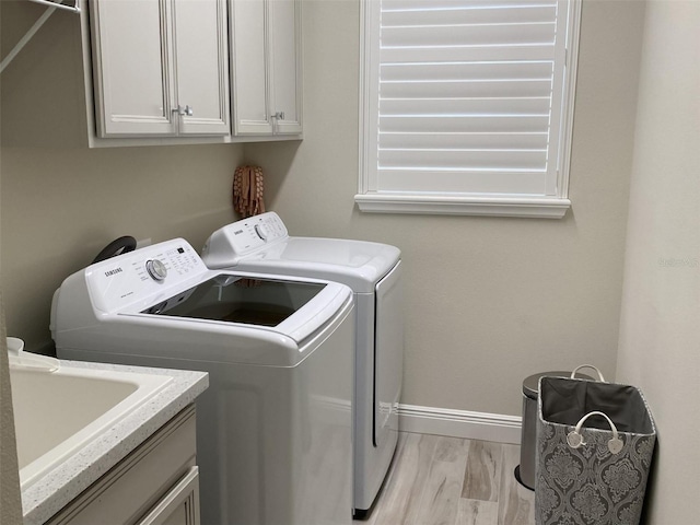 laundry room with light hardwood / wood-style floors, cabinets, sink, and washing machine and dryer