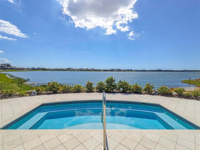 view of swimming pool featuring a water view and an in ground hot tub