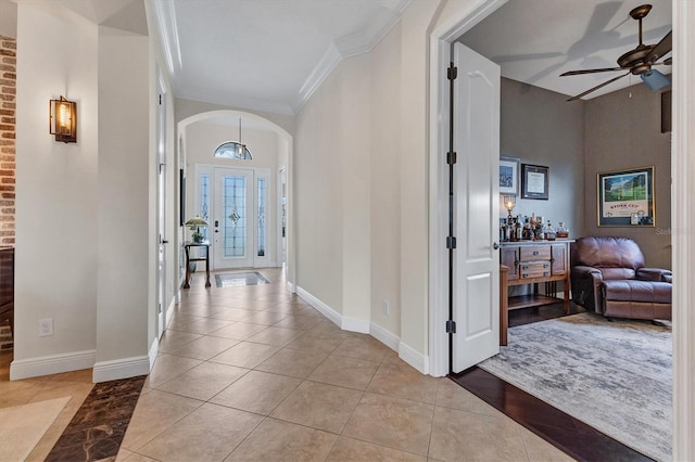 tiled foyer with ornamental molding and ceiling fan