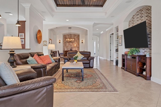 tiled living room featuring built in shelves, a raised ceiling, crown molding, and an inviting chandelier