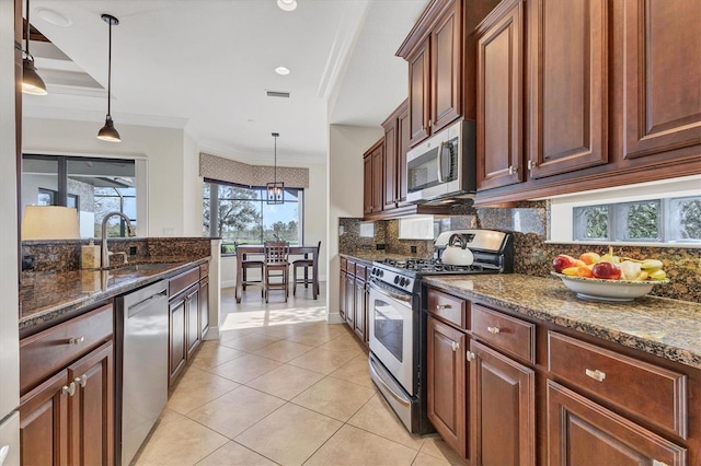 kitchen with stainless steel appliances, dark stone counters, sink, crown molding, and pendant lighting