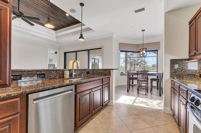 kitchen with stainless steel appliances, sink, decorative light fixtures, and dark stone countertops