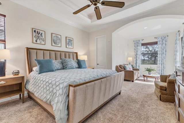 carpeted bedroom with a tray ceiling, ceiling fan, and crown molding