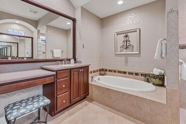 bathroom with tile patterned flooring, vanity, and a relaxing tiled tub