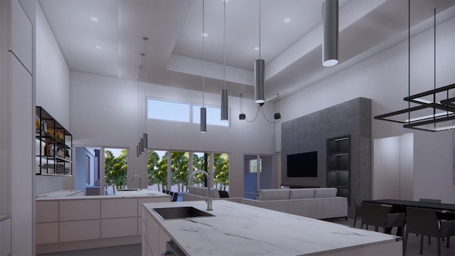 kitchen with white cabinets, sink, light stone counters, and a towering ceiling