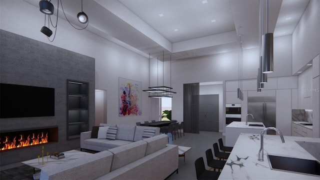 living room featuring a high ceiling, concrete flooring, sink, and a large fireplace