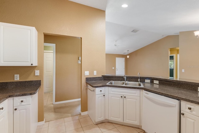 kitchen with lofted ceiling, white dishwasher, sink, light tile patterned flooring, and white cabinetry