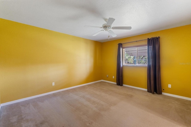 spare room with ceiling fan, a textured ceiling, and light colored carpet