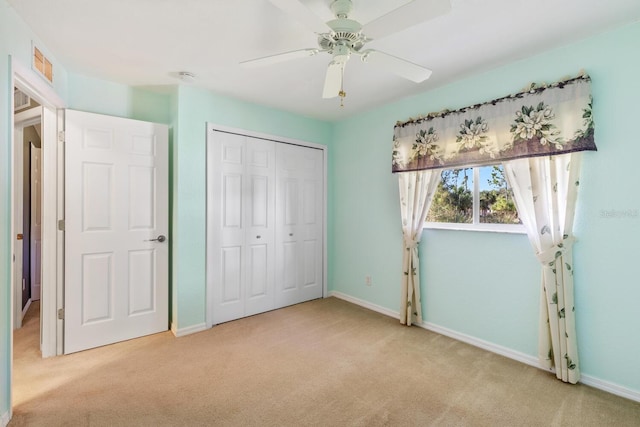 unfurnished bedroom with ceiling fan, light carpet, and a closet