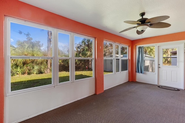 unfurnished sunroom featuring ceiling fan and a healthy amount of sunlight