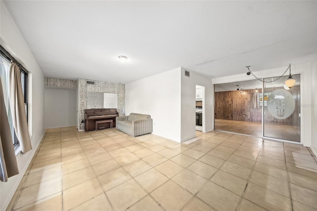 unfurnished living room with wood walls and light tile patterned flooring