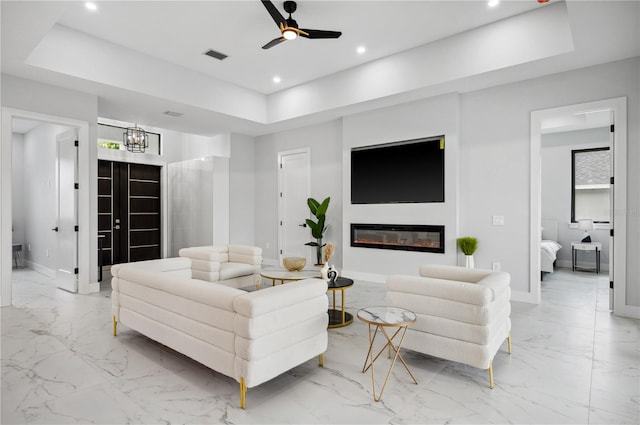 living room with a tray ceiling and ceiling fan