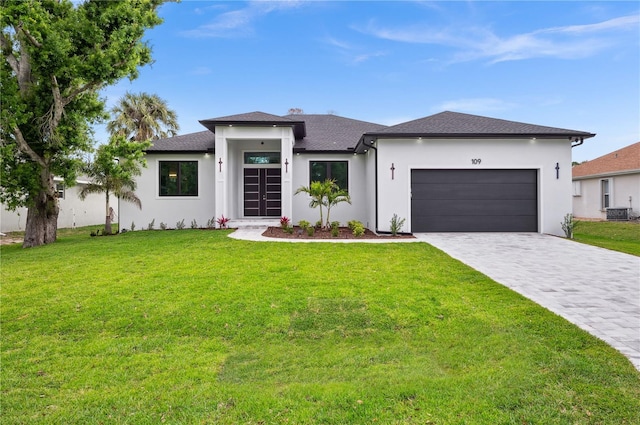 prairie-style house with stucco siding, a garage, a front lawn, and decorative driveway