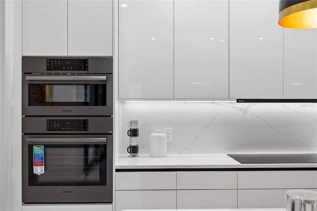 kitchen with black electric cooktop, modern cabinets, double oven, and white cabinets