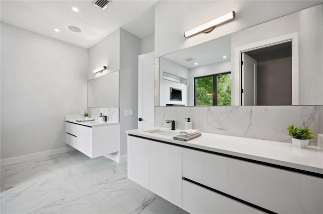 full bath with baseboards, a sink, marble finish floor, and two vanities