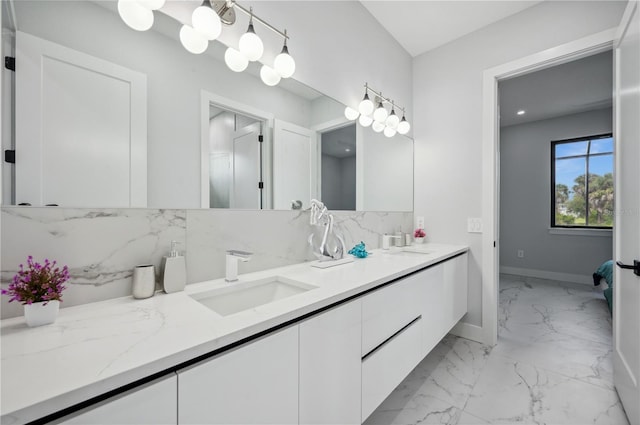 bathroom with a sink, baseboards, double vanity, and marble finish floor