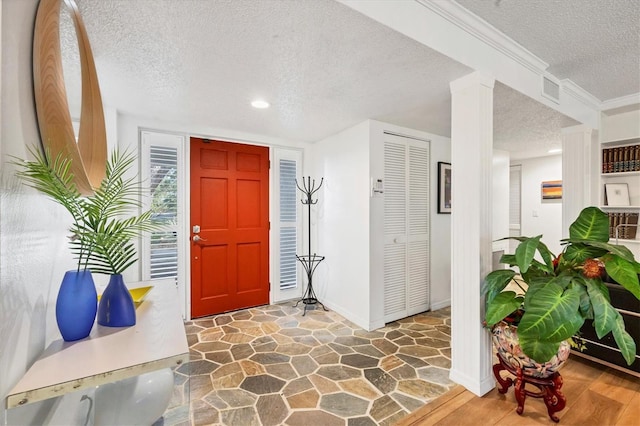 foyer with dark wood-type flooring, a textured ceiling, and decorative columns