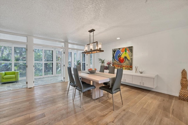 dining room with a chandelier, a textured ceiling, a wall of windows, and light hardwood / wood-style flooring