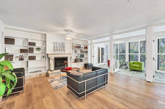 living room featuring ceiling fan, a textured ceiling, and light wood-type flooring