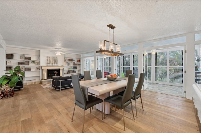 dining room with light hardwood / wood-style floors, ceiling fan with notable chandelier, and a textured ceiling