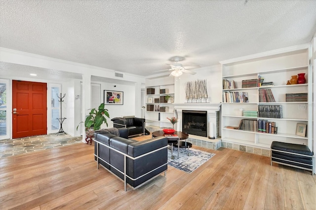 living room featuring a tiled fireplace, a textured ceiling, and light hardwood / wood-style flooring