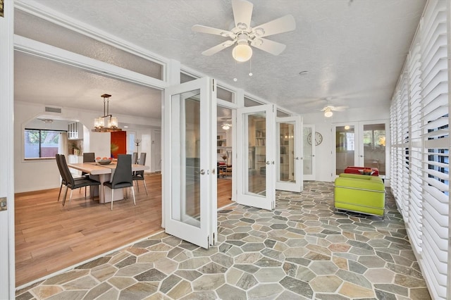 sunroom with ceiling fan with notable chandelier and french doors