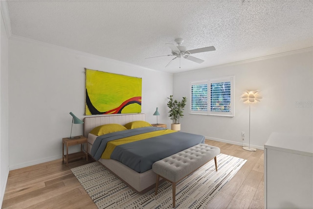 bedroom featuring a textured ceiling, light wood-type flooring, ornamental molding, and ceiling fan